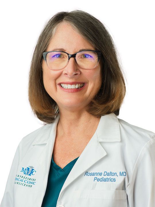 A woman wearing glasses and a white lab coat is smiling for the camera.