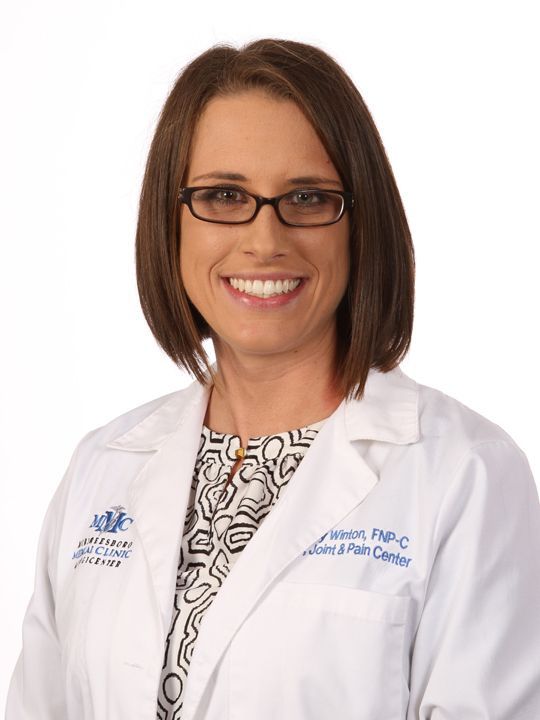 A smiling woman wearing glasses and a white lab coat