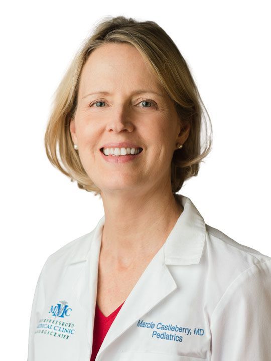 A woman in a white lab coat is smiling for the camera