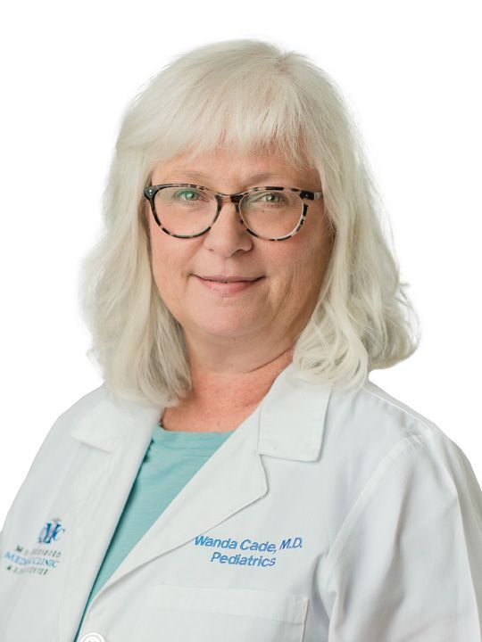 A woman wearing glasses and a white lab coat is smiling for the camera.