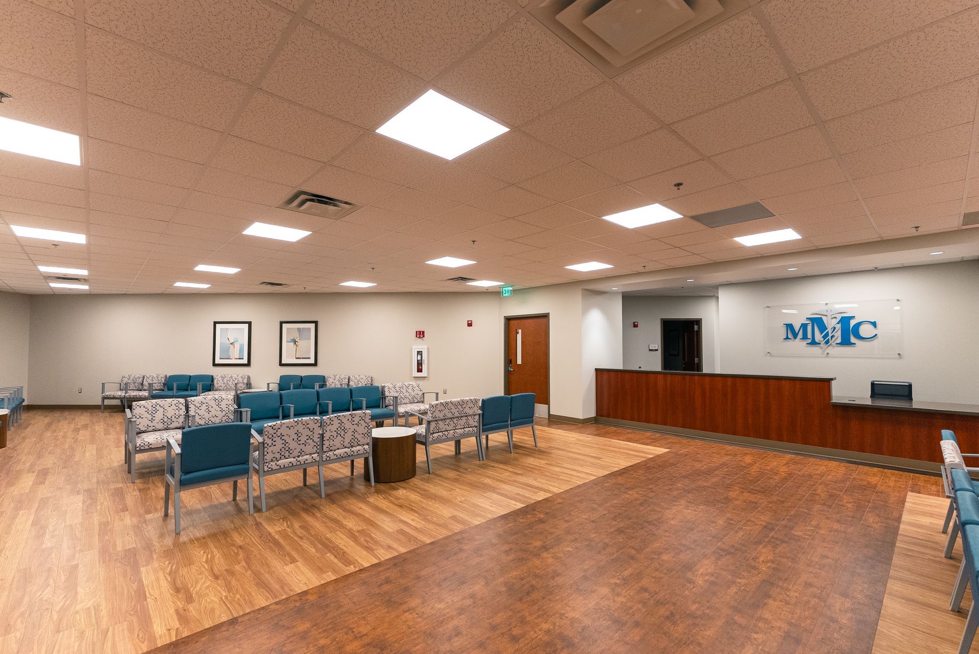 A large waiting room with lots of chairs and a counter.