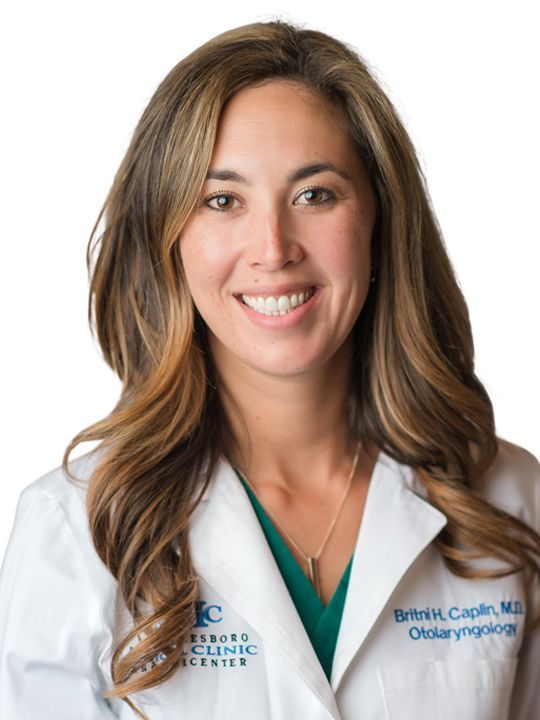 A woman in a white lab coat is smiling for the camera