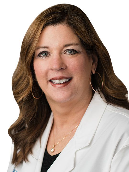 A woman in a white lab coat is smiling for the camera.