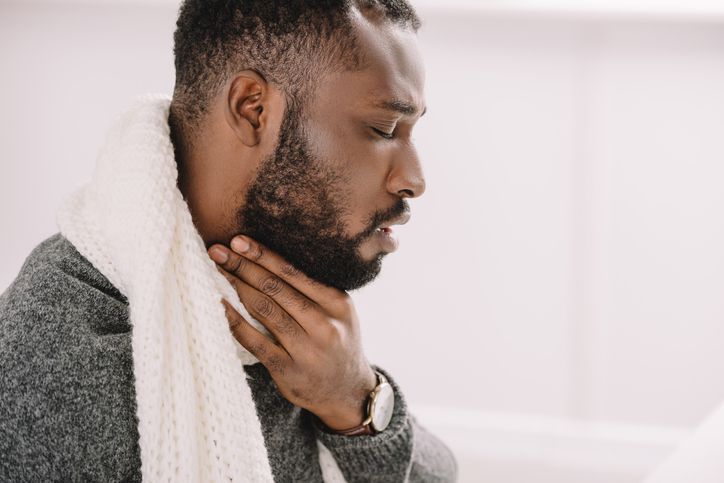 a man with a scarf around his neck is coughing