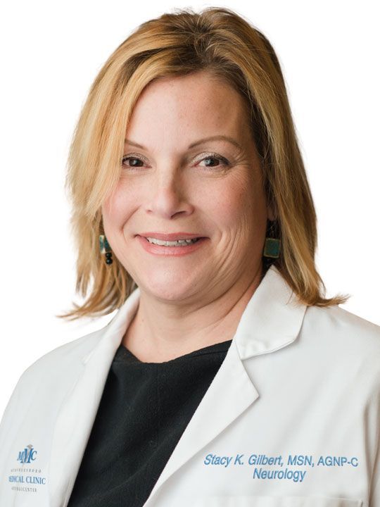 A woman is wearing a white lab coat and smiling