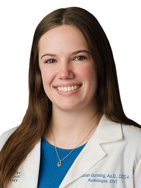 A woman in a white lab coat is smiling for the camera.