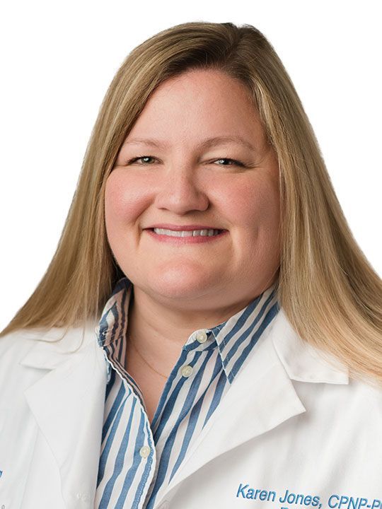 A woman in a white lab coat is smiling for the camera