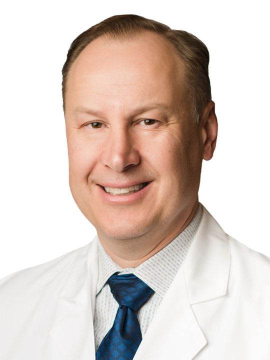 A woman in a white lab coat is smiling for the camera.