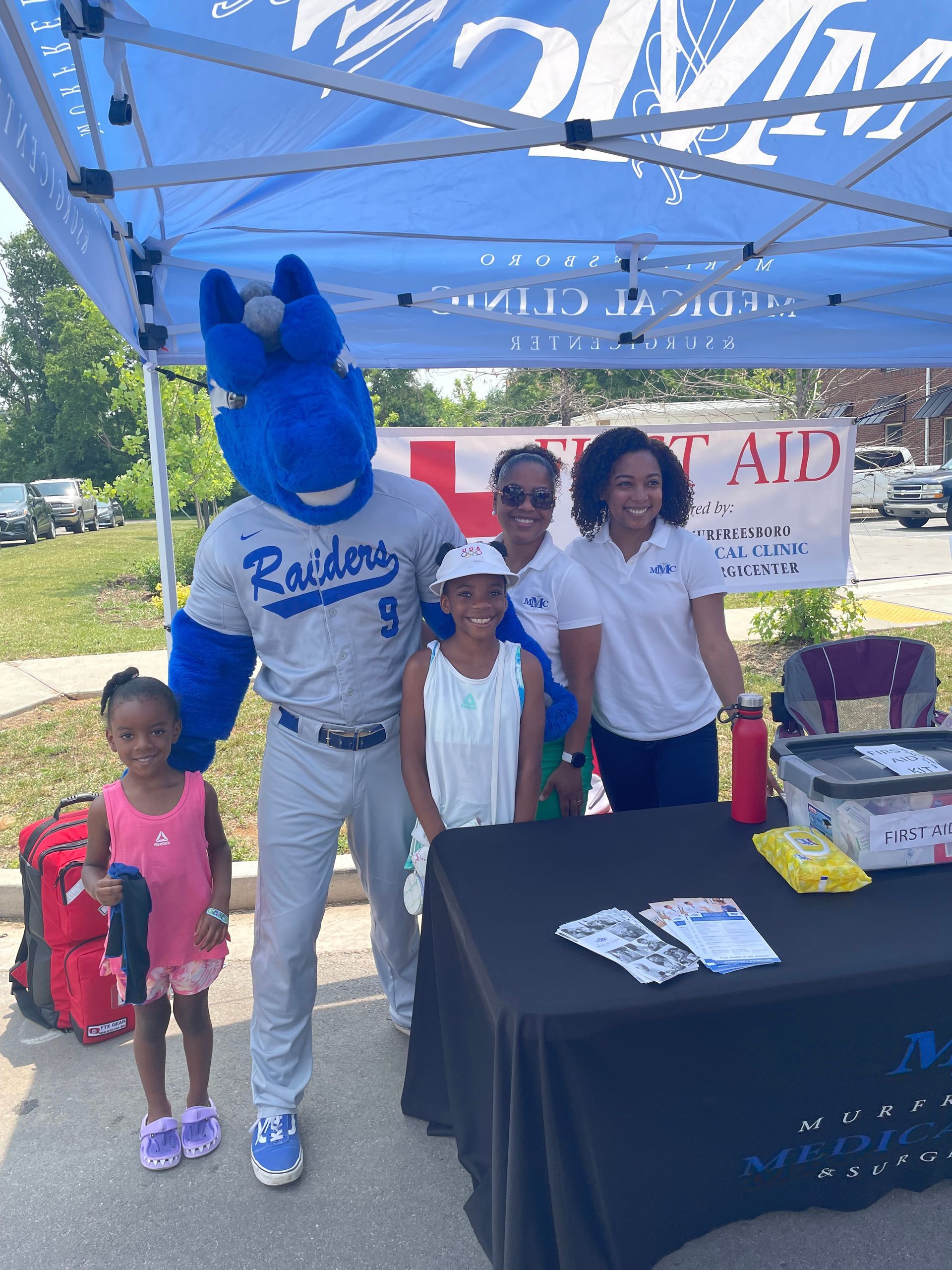 A group of people standing around a table with a mascot wearing a raiders jersey