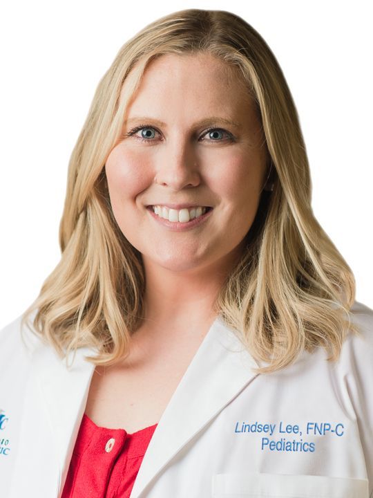 A woman in a white lab coat is smiling and wearing a red shirt.