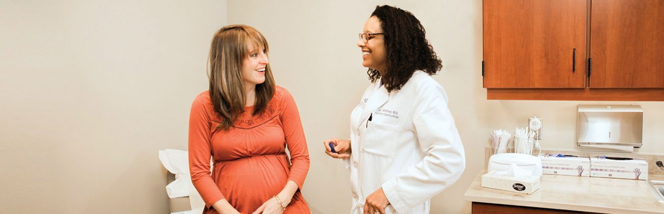 a pregnant woman is talking to a doctor in a doctor 's office .