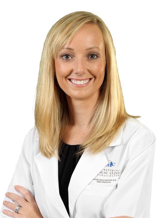 A woman in a white lab coat is smiling for the camera.