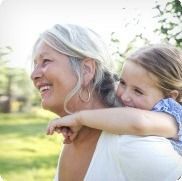 A woman is carrying a little girl on her back.