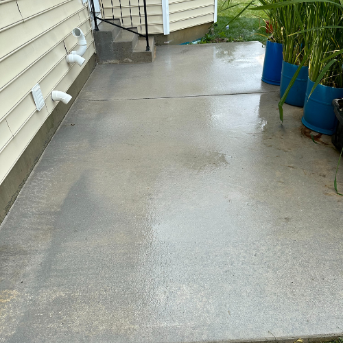 A concrete walkway next to a house with potted plants