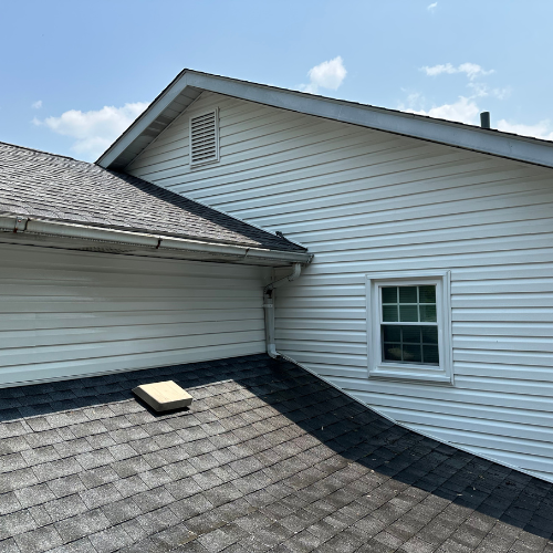 A white house with a gray roof and a window on the side.