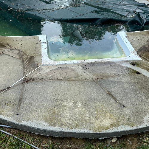 A concrete patio with a swimming pool in the background.