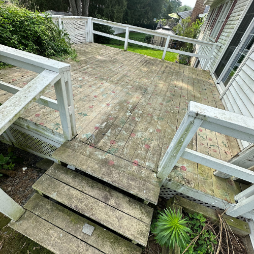A wooden deck with stairs leading up to it and a white railing.