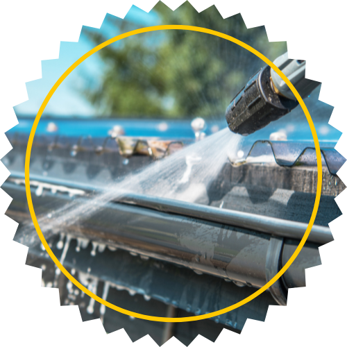 A person is cleaning a gutter with a high pressure washer.