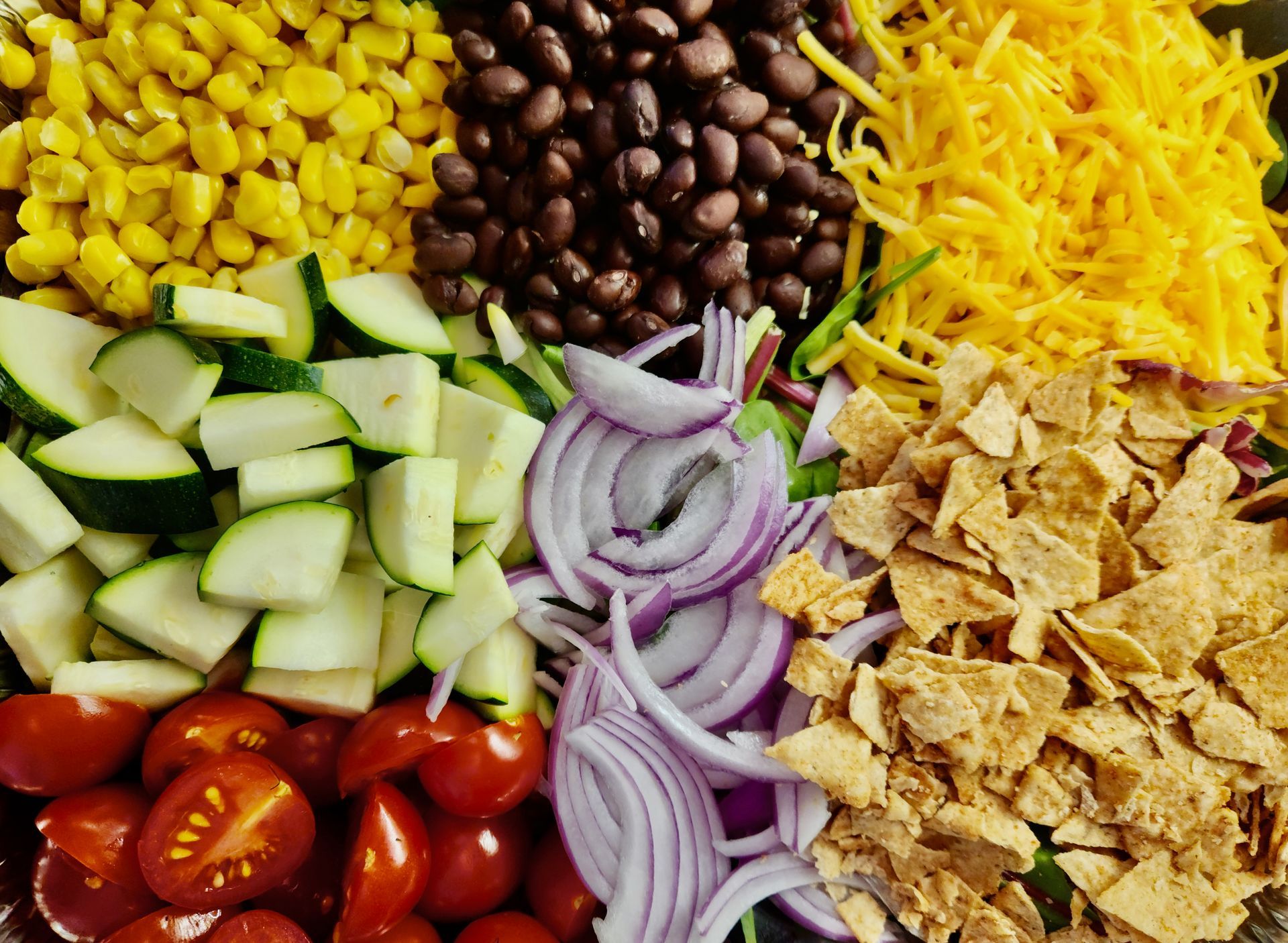 A salad with tomatoes , onions , corn , black beans and cheese