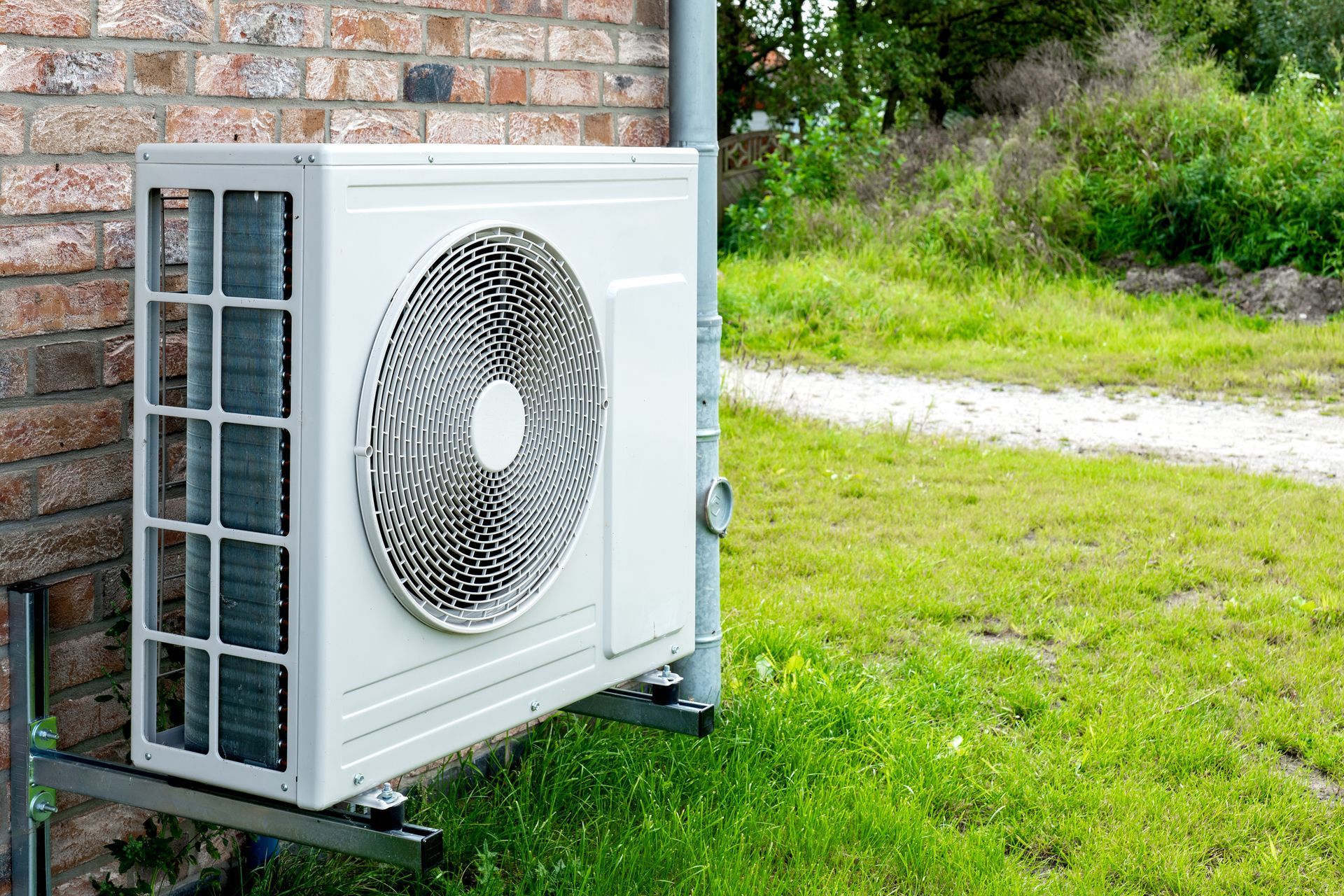 A white air conditioner is sitting on the side of a brick building.