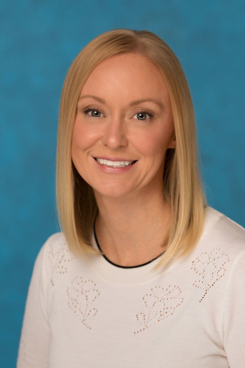 The woman is wearing a white sweater and smiling for the camera.