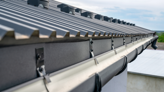Row of gray roof-mounted solar panels on a building against a cloudy sky