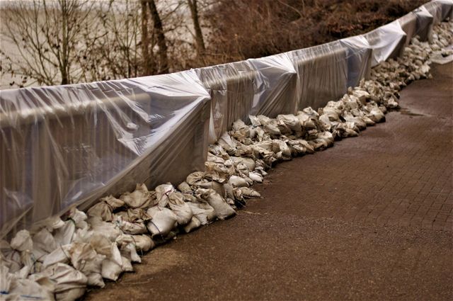 Plastic sheeting and sandbags lining a roadside embankment to prevent erosion