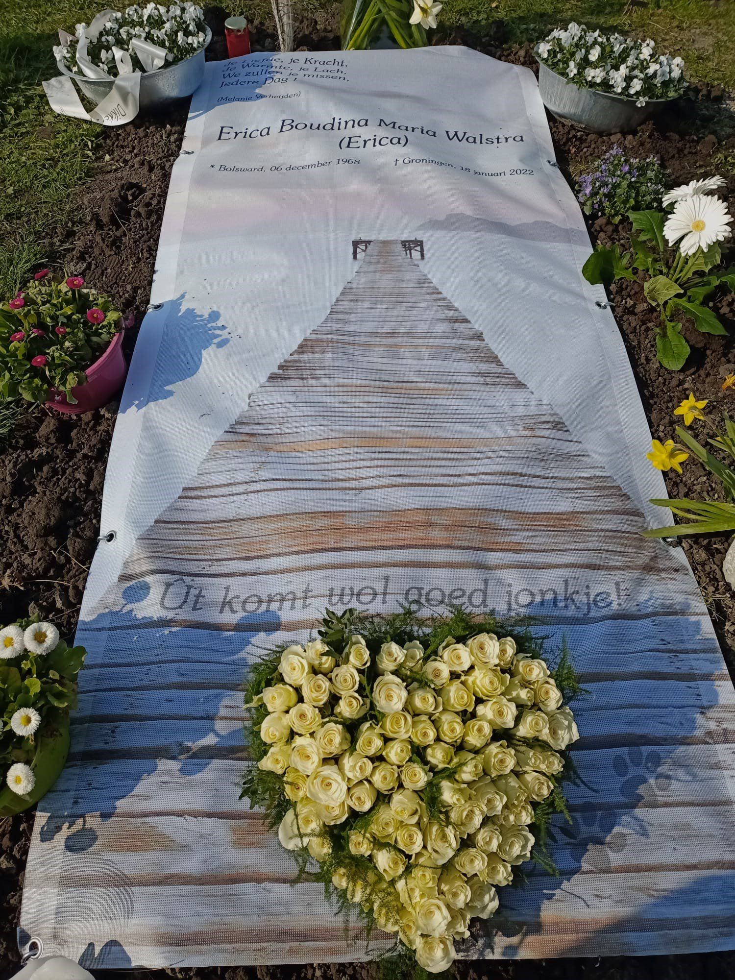 Een graf met daarop een hartvormige bloemenkrans.