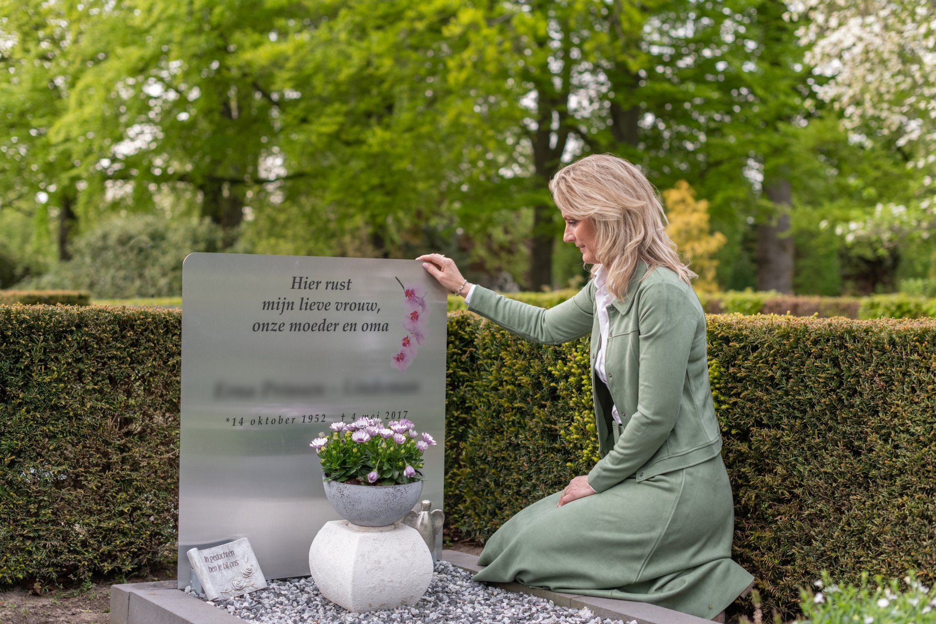 Grafmonument. Een vrouw knielt voor een graf op een begraafplaats.