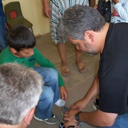 A man in a black shirt is kneeling down next to a boy in a green shirt