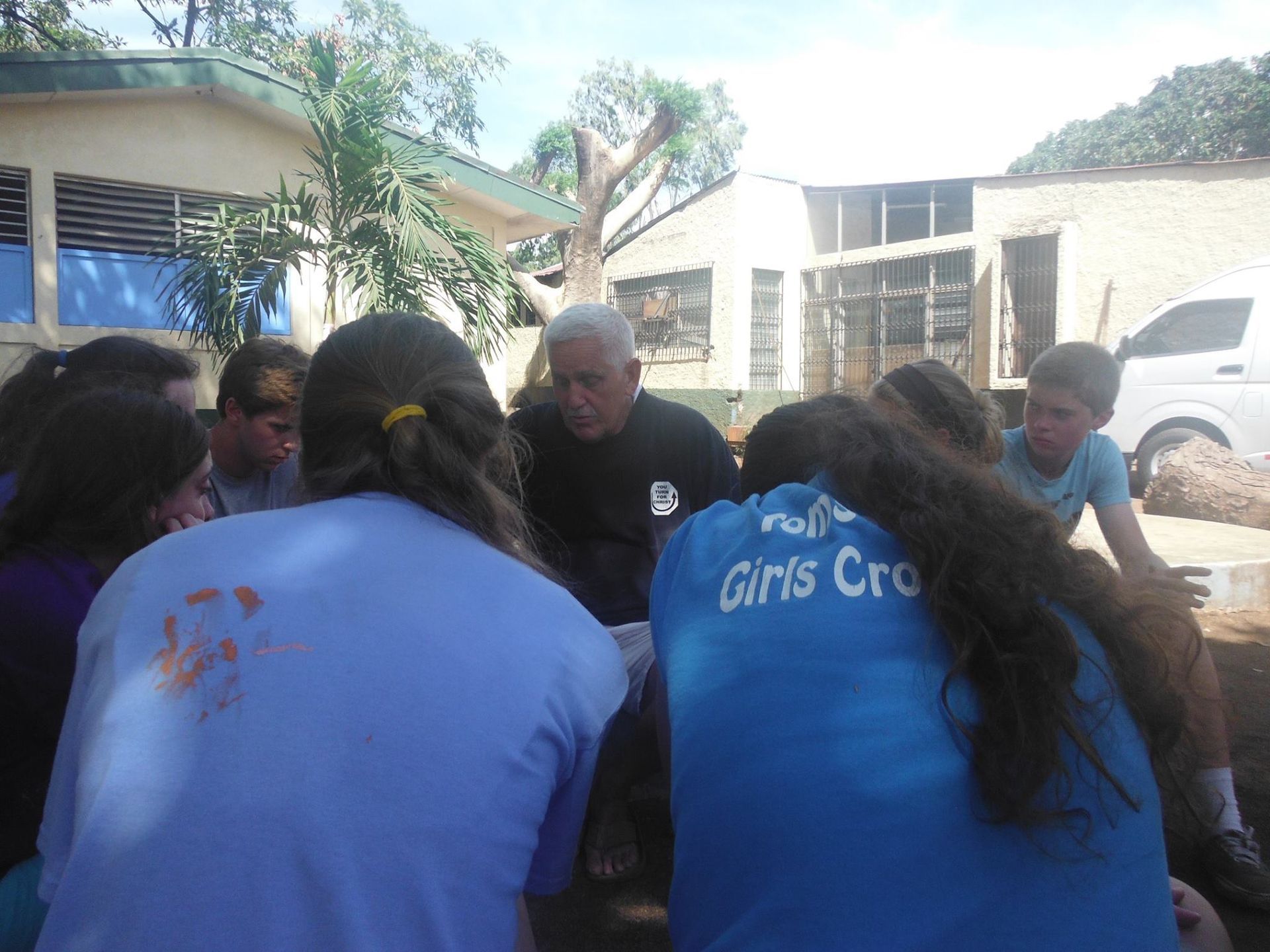 A group of people are sitting in a circle with one wearing a blue shirt that says girls crew