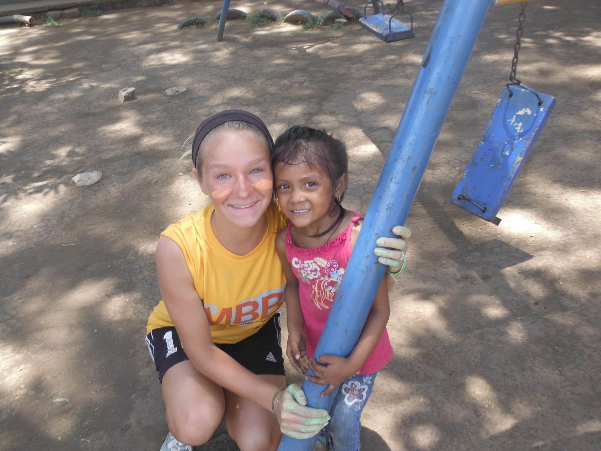A girl in a yellow shirt that says vibe is hugging a little girl