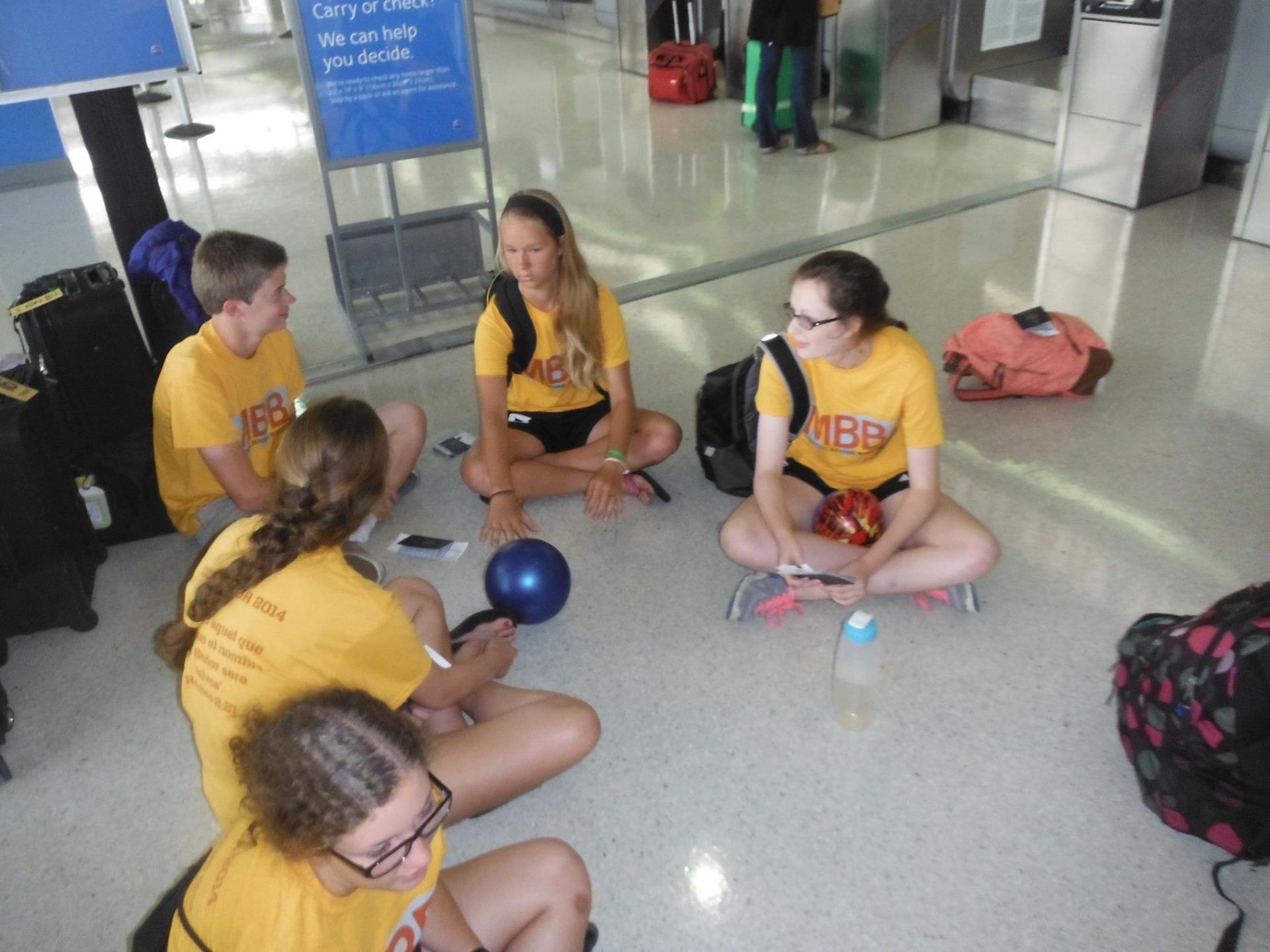 A group of people in yellow shirts are sitting on the floor