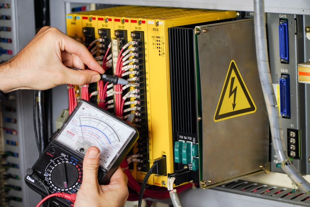 A Person Uses an Analog Multimeter to Test Connections on a Industrial Plc Control — DLG Electrical and Solar In Wyong, NSW