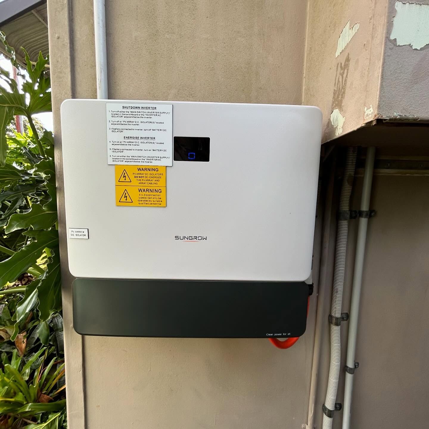 A White Battery Box With a Yellow Sticker on It is Hanging on a Wall — DLG Electrical & Solar In Wyong, NSW