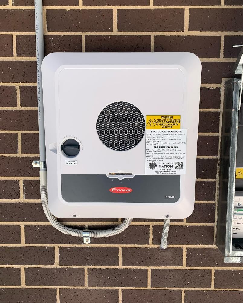 A Solar Battery is Attached to a Brick Wall — DLG Electrical & Solar In Wyong, NSW