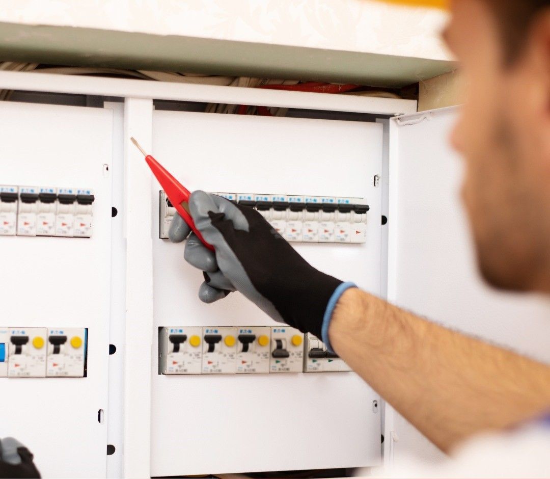 A Man is Working on an Electrical Box With a Screwdriver — DLG Electrical & Solar In Wyong, NSW