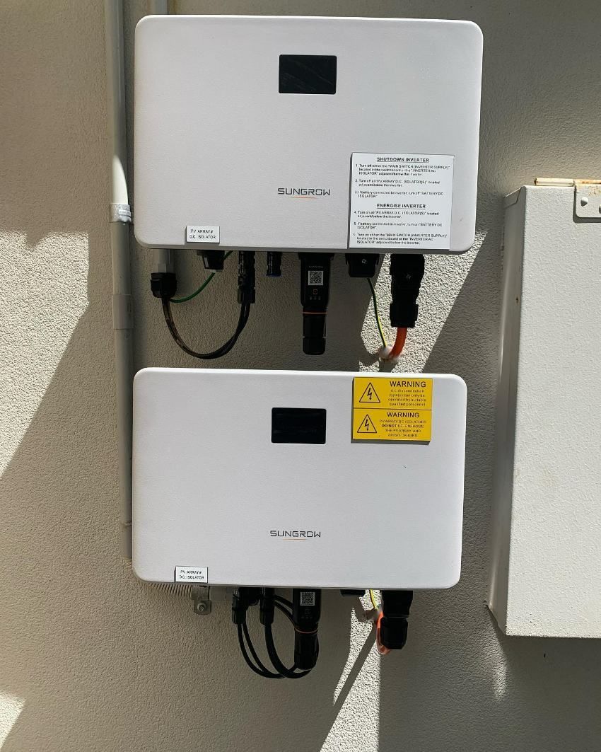 Two White Solar Inverters Are Hanging on a Wall — DLG Electrical & Solar In Newcastle, NSW