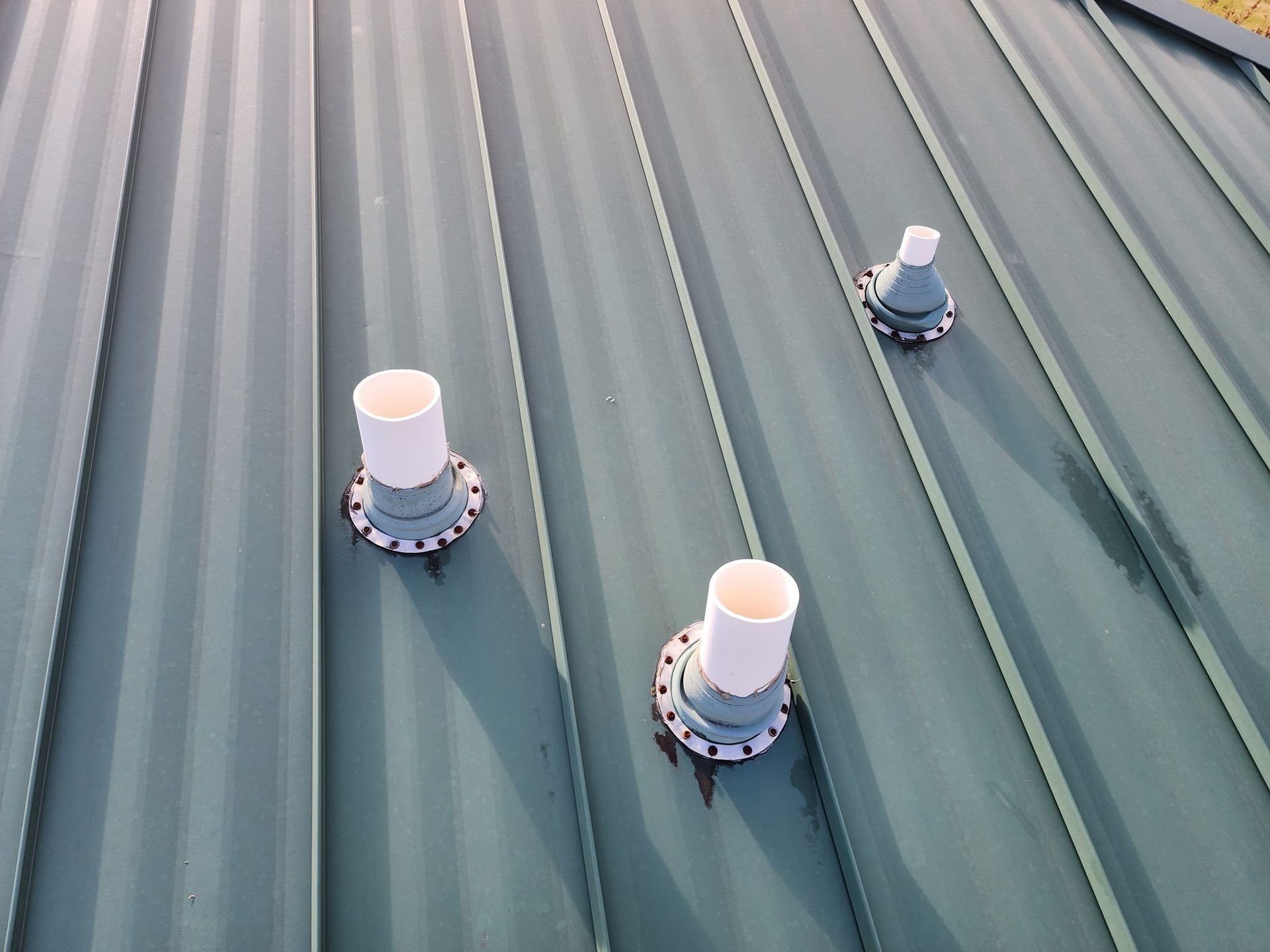 Three pipes are sitting on top of a metal roof.