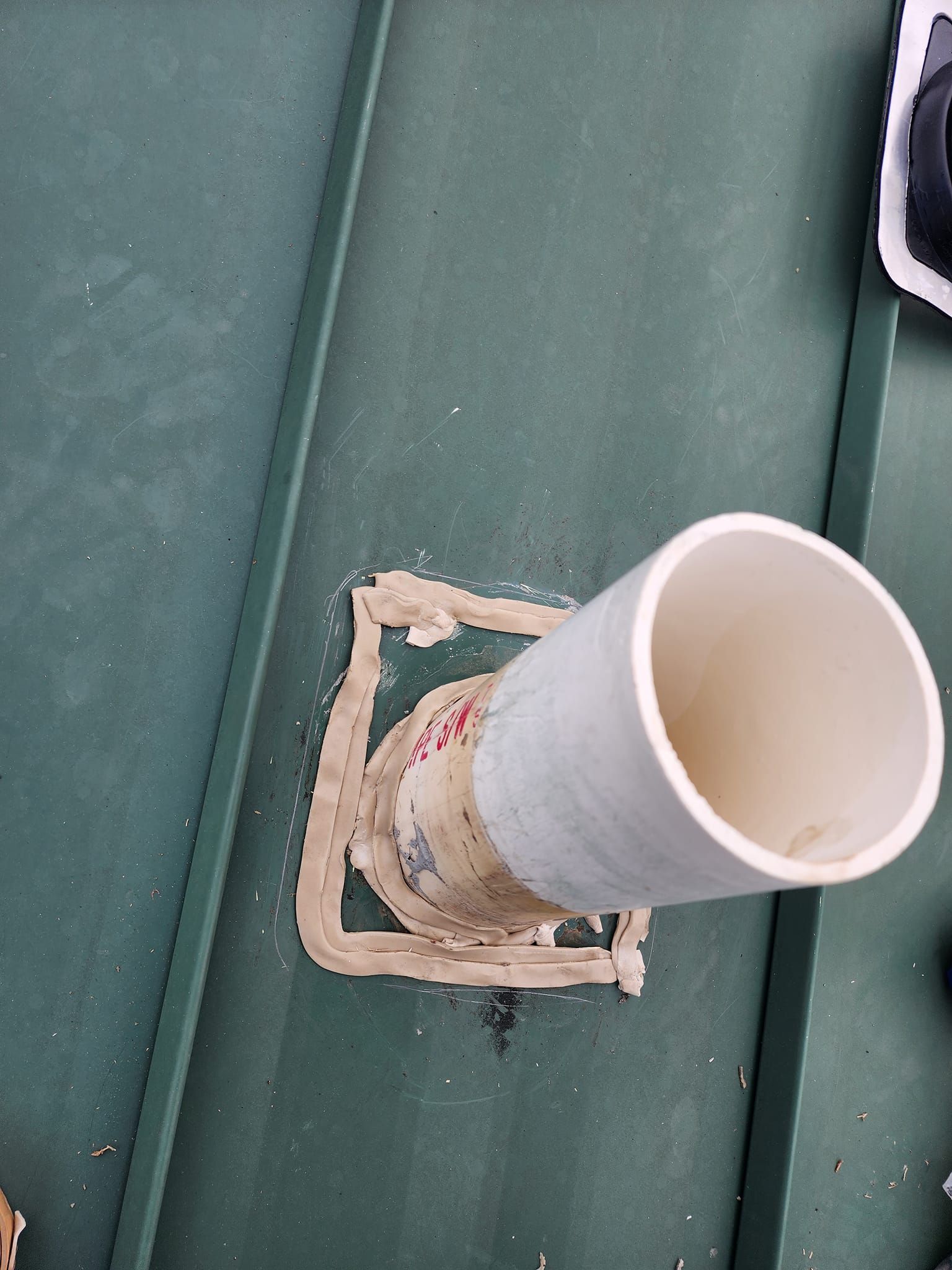 A white pvc pipe is sitting on top of a green roof.