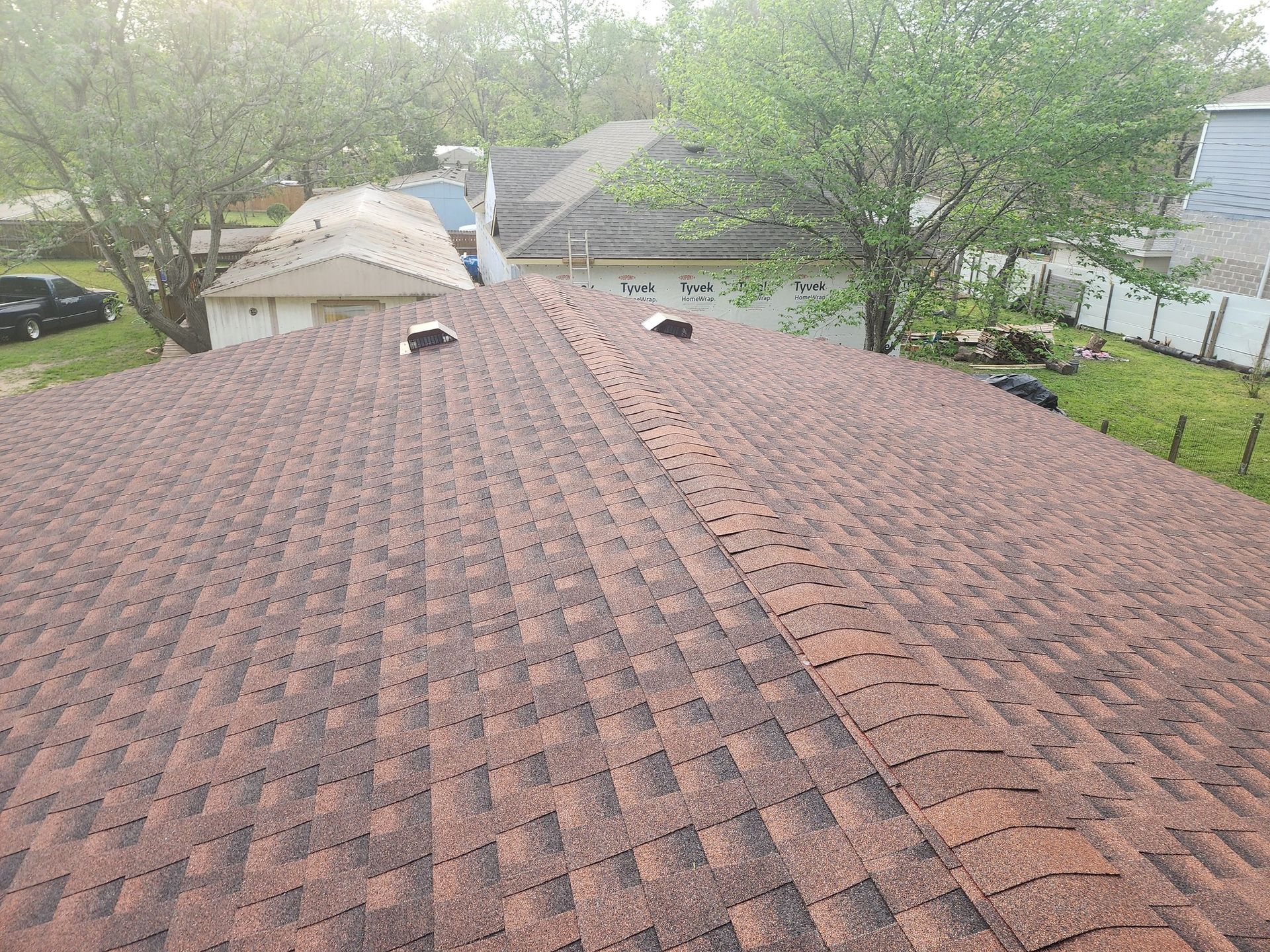 An aerial view of a roof of a house with trees in the background.