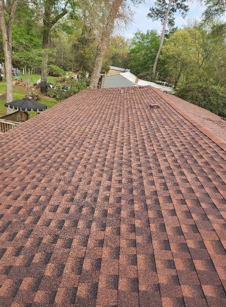 The roof of a house with a red roof and trees in the background.