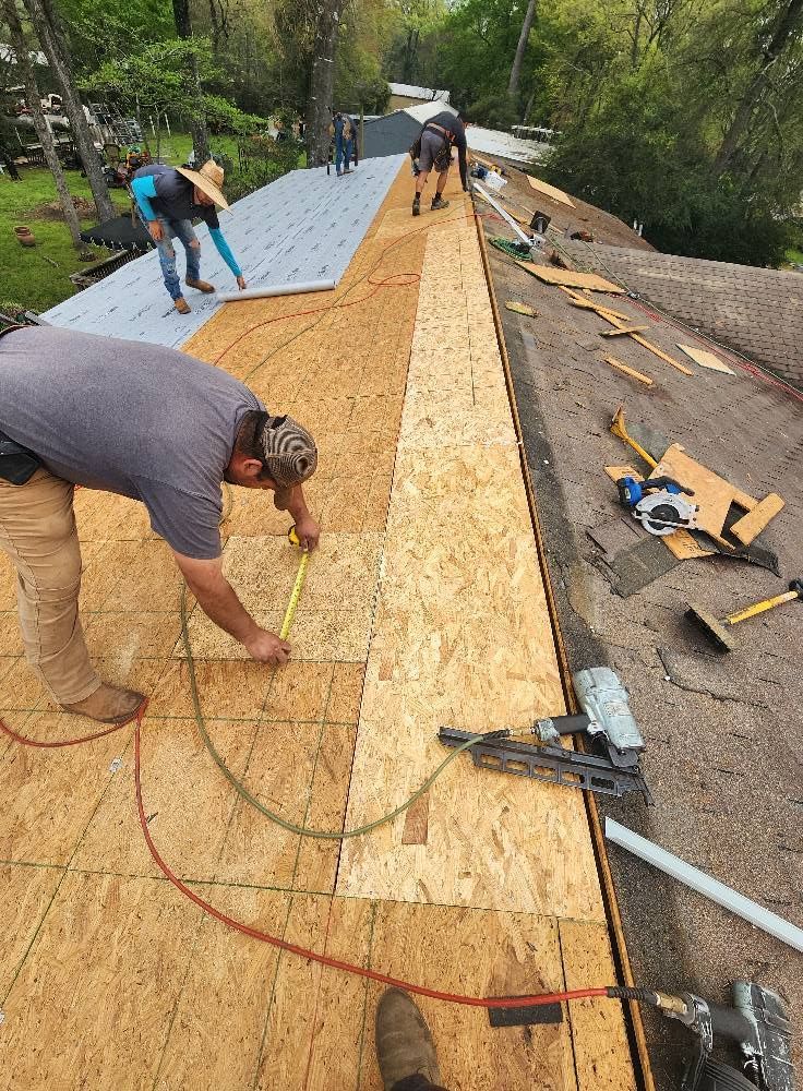 A man is measuring a piece of plywood on a roof.