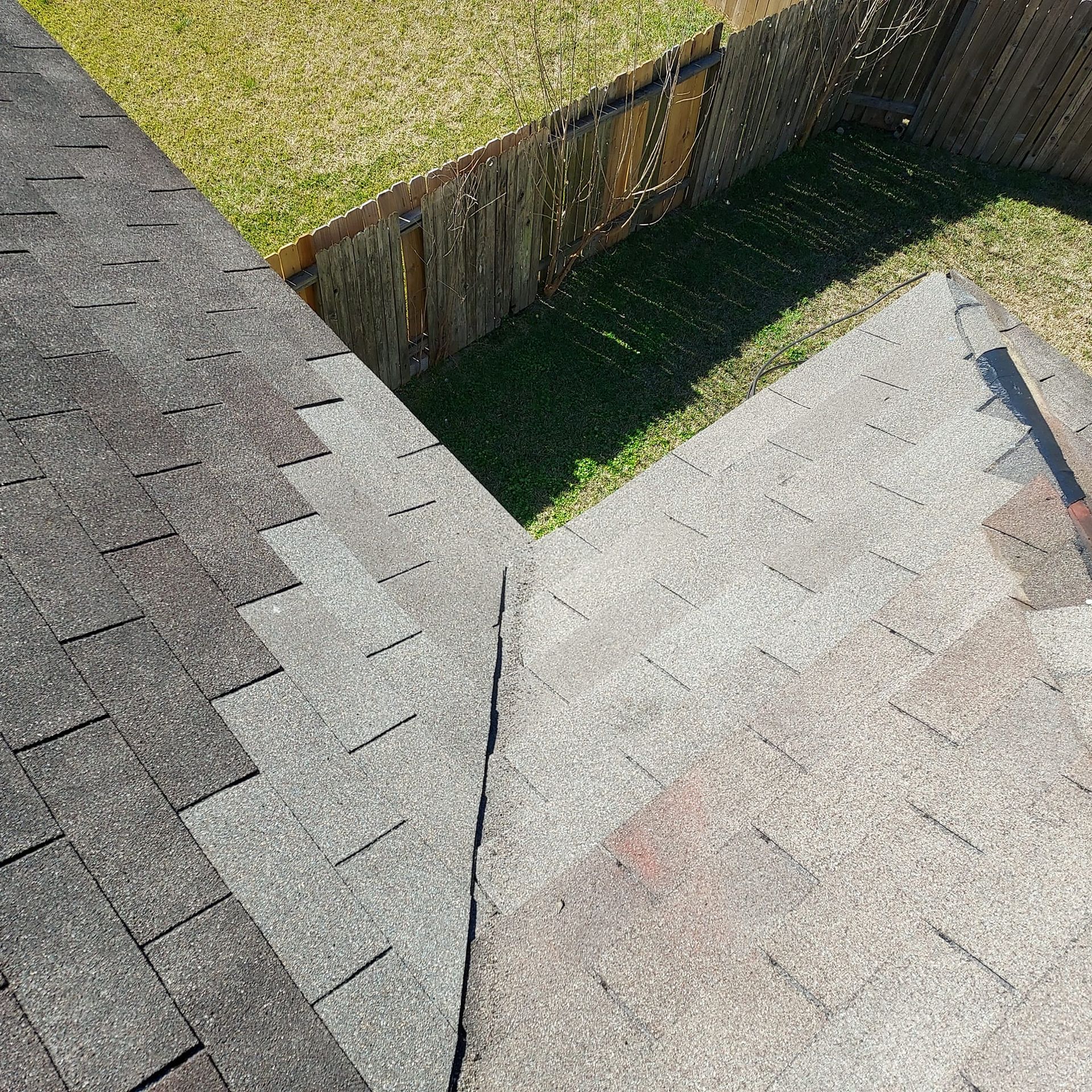 A roof with shingles on it and a fence in the background.