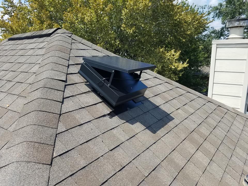 A roof with a vent on it and trees in the background.