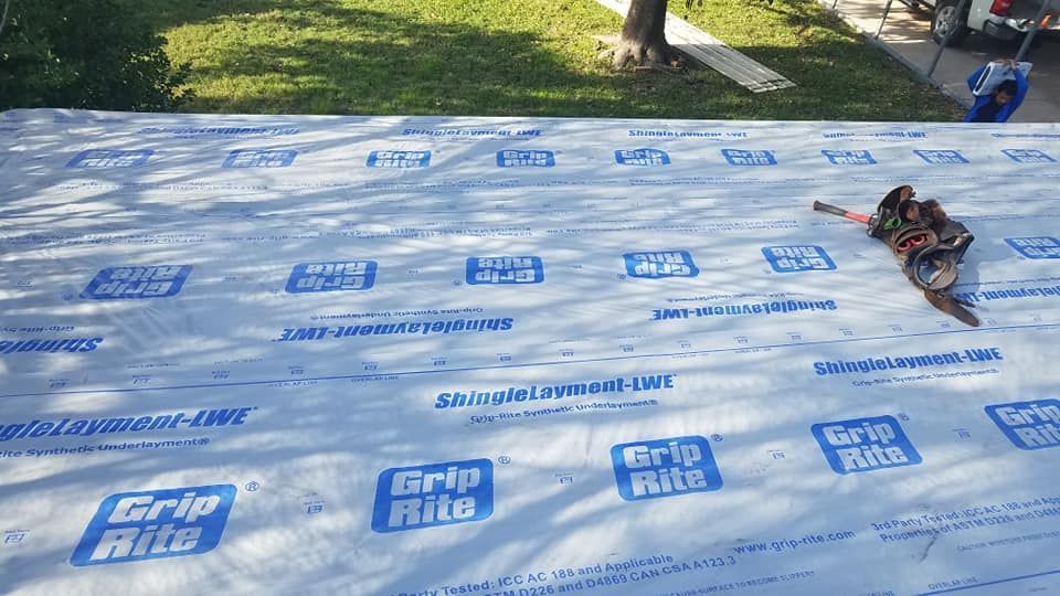 A roof is being covered with a piece of grip rite roofing paper.