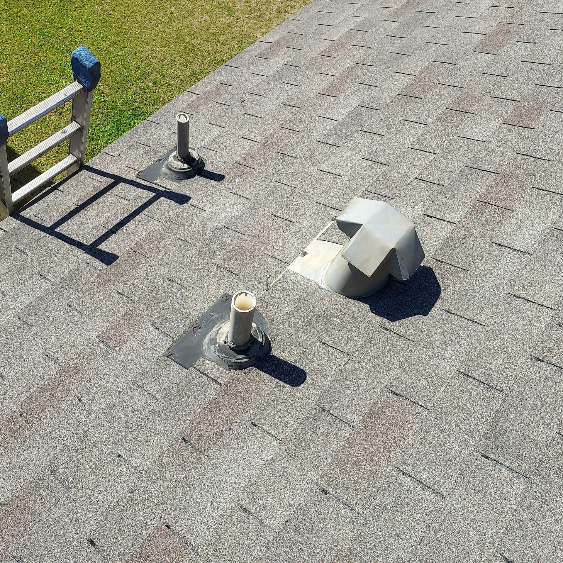 A roof with a ladder and a fan on it.