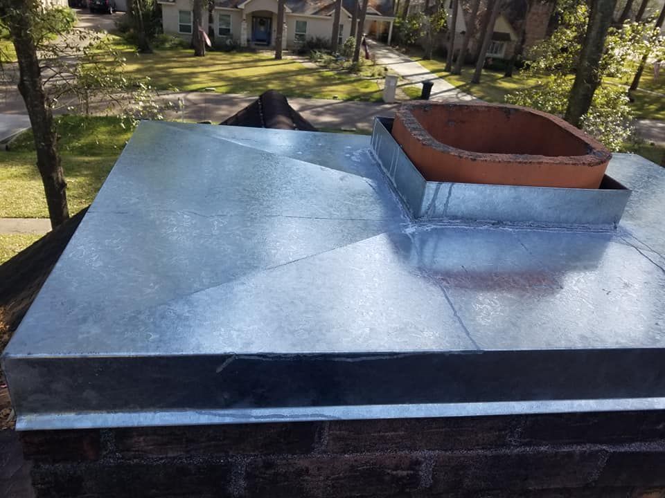 A brick chimney with a metal cover on top of it.