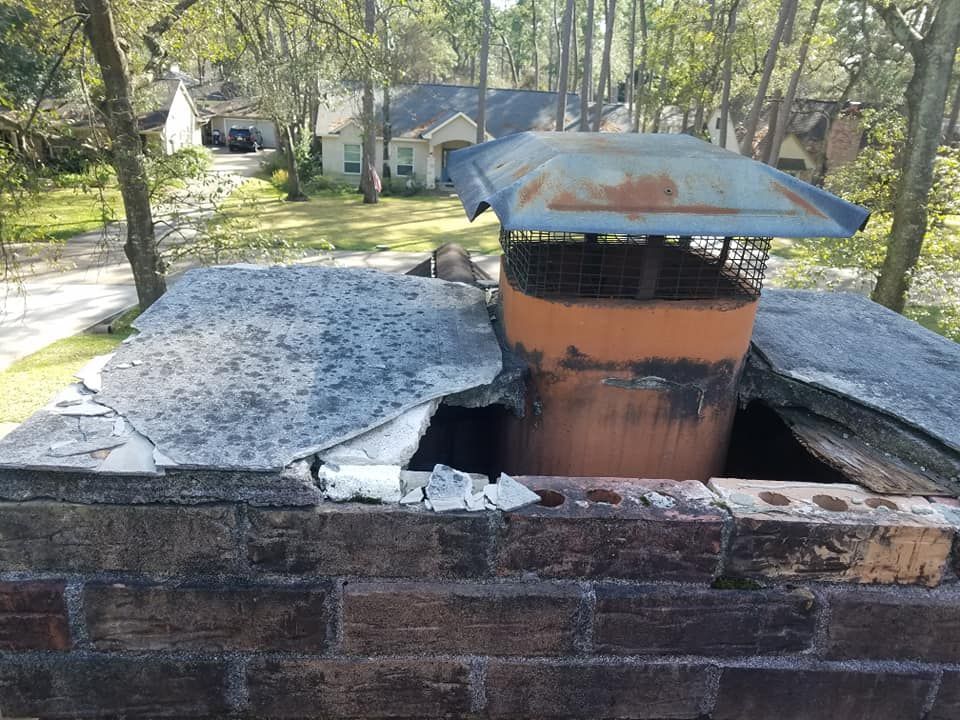 A chimney on top of a brick wall with a house in the background