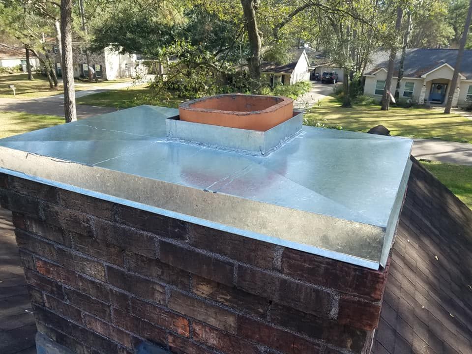 A brick chimney with a metal cover on top of it.